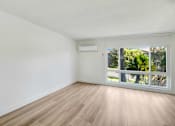 Thumbnail 6 of 23 - A room with wooden flooring and a sliding glass door leading to a balcony.