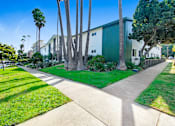 Thumbnail 17 of 17 - A green building with a white fence and a green lawn in front.