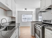 Thumbnail 9 of 17 - A modern kitchen with stainless steel appliances and wooden floors.