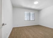 Thumbnail 12 of 22 - A room with a window and wooden flooring.