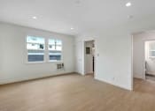 Thumbnail 1 of 22 - A large empty room with wooden floors and white walls.
