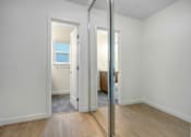 Thumbnail 6 of 22 - A room with a wooden floor and white walls, with a mirror on the wall.