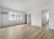 Thumbnail 15 of 22 - A spacious room with wooden flooring and white walls.