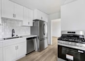 Thumbnail 17 of 22 - A modern kitchen with white cabinets and stainless steel appliances.