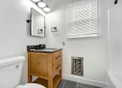 Thumbnail 20 of 22 - A white bathroom with a wooden vanity and a white toilet.