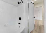 Thumbnail 21 of 22 - A white bathroom with a tub and a door.