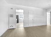 Thumbnail 12 of 21 - A white room with a wooden floor and a mirror on the wall.
