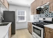 Thumbnail 13 of 21 - A kitchen with a black refrigerator, stove, and oven.