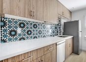 Thumbnail 14 of 21 - A kitchen with wooden cabinets and a tile backsplash.