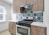 Thumbnail 15 of 21 - A kitchen with a stove and a tile backsplash.