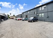 Thumbnail 20 of 21 - A parking lot with several cars and a building in the background.