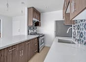 Thumbnail 15 of 37 - A kitchen with brown cabinets and a white countertop.