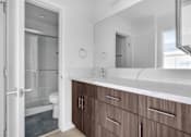 Thumbnail 18 of 37 - A bathroom with a white counter top and brown drawers.