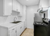 Thumbnail 3 of 37 - A kitchen with white cabinets and a black stove top oven.