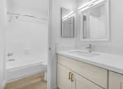 Thumbnail 6 of 37 - A white bathroom with a tub, sink, and mirror.