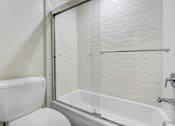 Thumbnail 27 of 37 - A white toilet sits next to a glass shower door.
