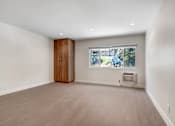 Thumbnail 8 of 37 - A room with a window and a wooden cabinet.