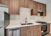 Thumbnail 10 of 37 - A kitchen with wooden cabinets and a stainless steel refrigerator.