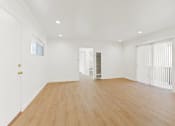Thumbnail 3 of 12 - a living room with wood floors and white walls and a sliding glass door