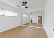Thumbnail 5 of 12 - an empty living room with mirrored doors and a ceiling fan