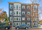 Thumbnail 12 of 43 - A grey building with a tree in front of it.