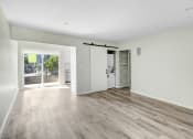 Thumbnail 5 of 47 - an empty living room with white walls and a sliding door to a kitchen