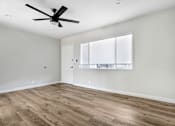 Thumbnail 24 of 47 - A room with a ceiling fan and wooden flooring.