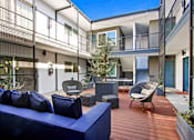 Thumbnail 38 of 47 - A blue couch is on a wooden deck in front of a building.