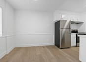 Thumbnail 3 of 23 - A kitchen with a stainless steel refrigerator and wooden flooring.