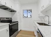 Thumbnail 6 of 23 - A kitchen with white cabinets and a black oven.