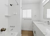 Thumbnail 8 of 23 - A white bathroom with a tub, sink, and mirror.