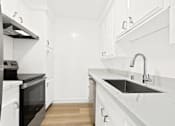 Thumbnail 14 of 23 - A modern kitchen with white cabinets and a black oven.