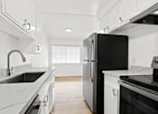Thumbnail 15 of 23 - A black refrigerator in a kitchen with white cabinets.