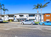 Thumbnail 20 of 23 - A parking lot with cars and a building in the background.