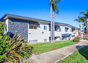 Thumbnail 23 of 23 - A modern building with a stone facade and palm trees in front.