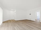 Thumbnail 13 of 23 - A room with wooden flooring and white walls.