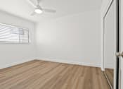 Thumbnail 16 of 23 - A room with a wooden floor and a ceiling fan.