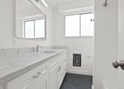 Thumbnail 17 of 23 - A white bathroom with a marble counter top and a large mirror.