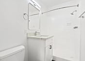 Thumbnail 19 of 23 - A white bathroom with a toilet, sink, and shower.