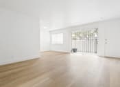 Thumbnail 12 of 39 - a living room with white walls and wooden floors and a door to a balcony