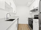 Thumbnail 5 of 39 - an all white kitchen with white cabinets and a black stove