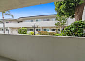 Thumbnail 30 of 39 - A white building with a balcony and a tree in front.