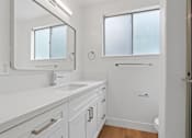 Thumbnail 34 of 39 - A white bathroom with a sink, mirror, and shower.