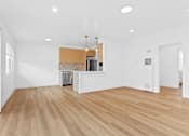 Thumbnail 23 of 39 - A kitchen area with wooden floors and white walls.