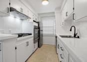 Thumbnail 5 of 11 - A kitchen with white cabinets and a black stove top.