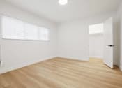 Thumbnail 7 of 11 - A room with wooden flooring and a window with blinds.