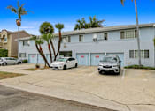 Thumbnail 10 of 11 - A white car is parked in front of a grey building with a palm tree.