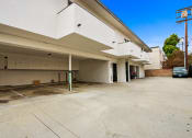 Thumbnail 3 of 3 - the parking lot of a white building with a car parked under it