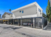 Thumbnail 34 of 34 - a white building with a gate and cars parked in front of it
