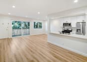 Thumbnail 13 of 34 - an empty living room with a kitchen and a door to a balcony